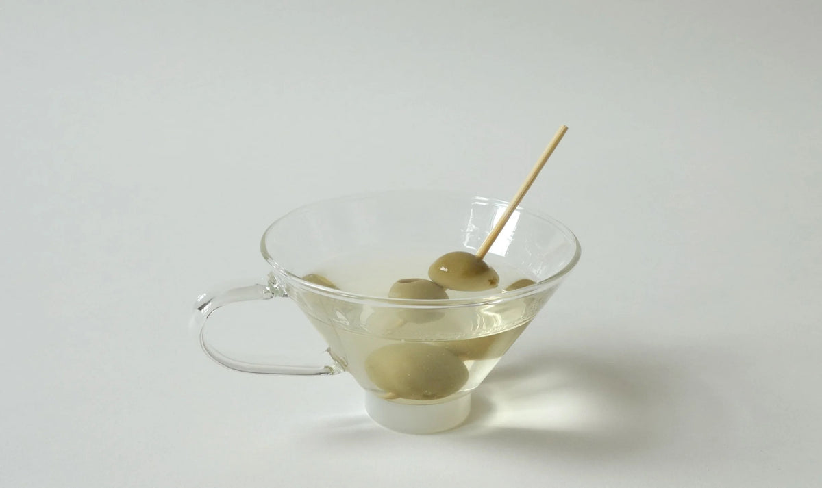 Glass with olives on a toothpick against a white background