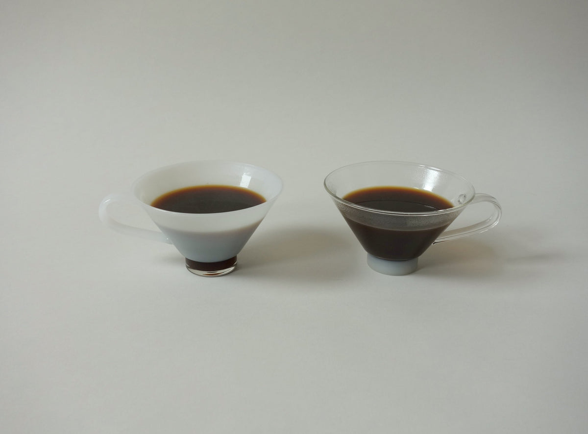 Two small cups filled with coffee on a light gray background
