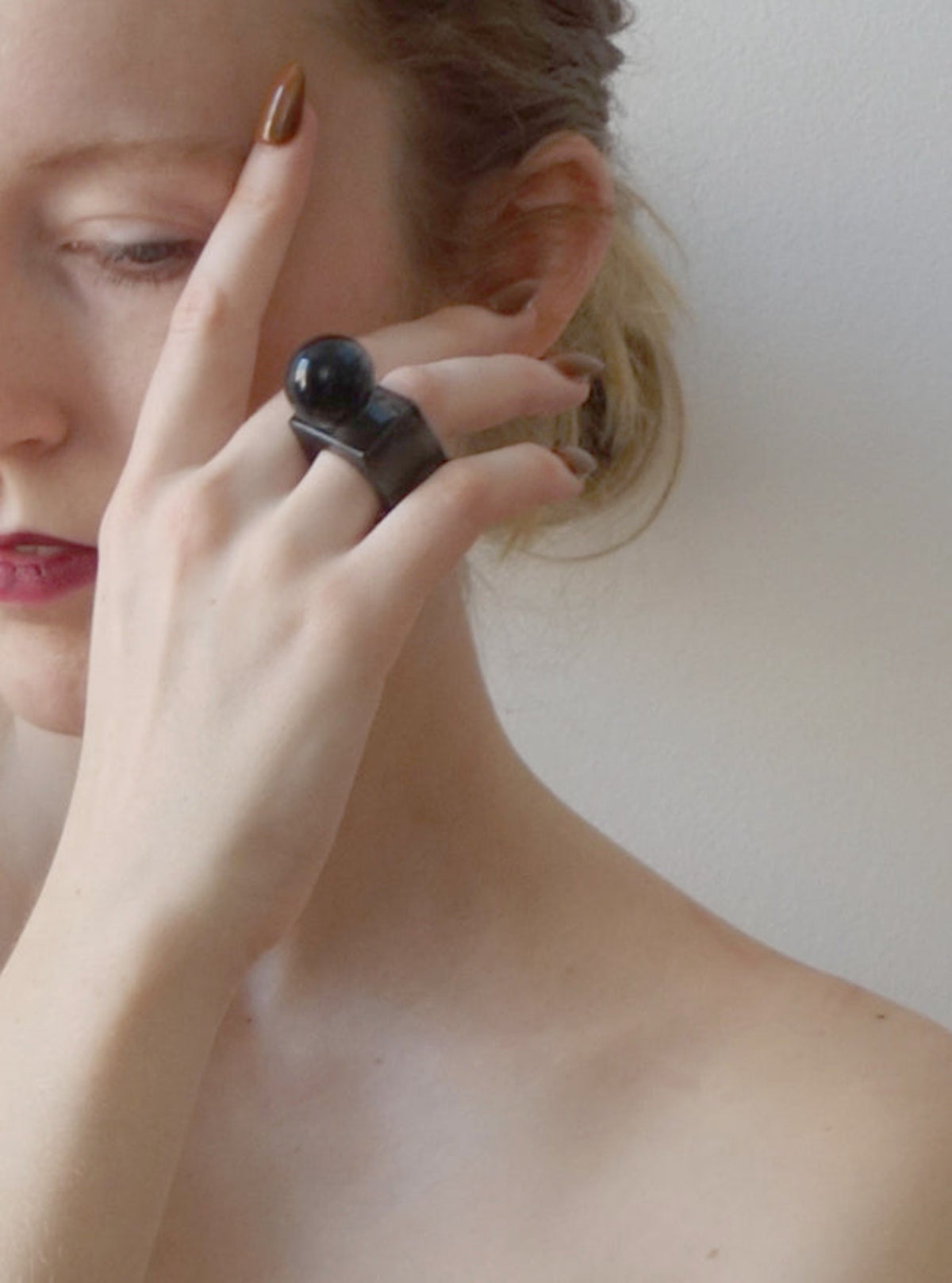 Woman wearing a glass black ring on her finger with a plain background