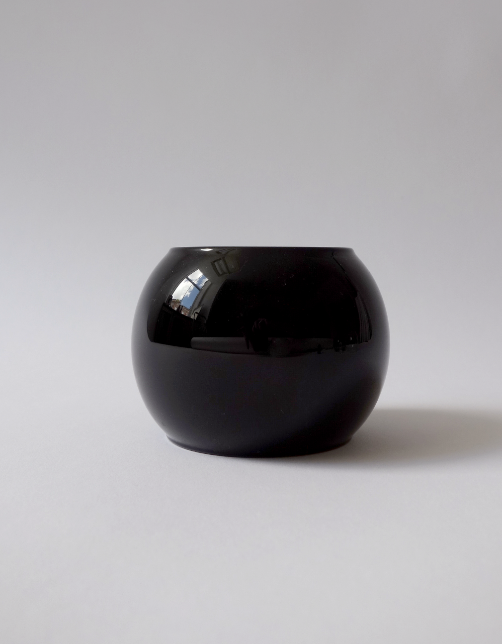 Black, glass bangle on a light gray background