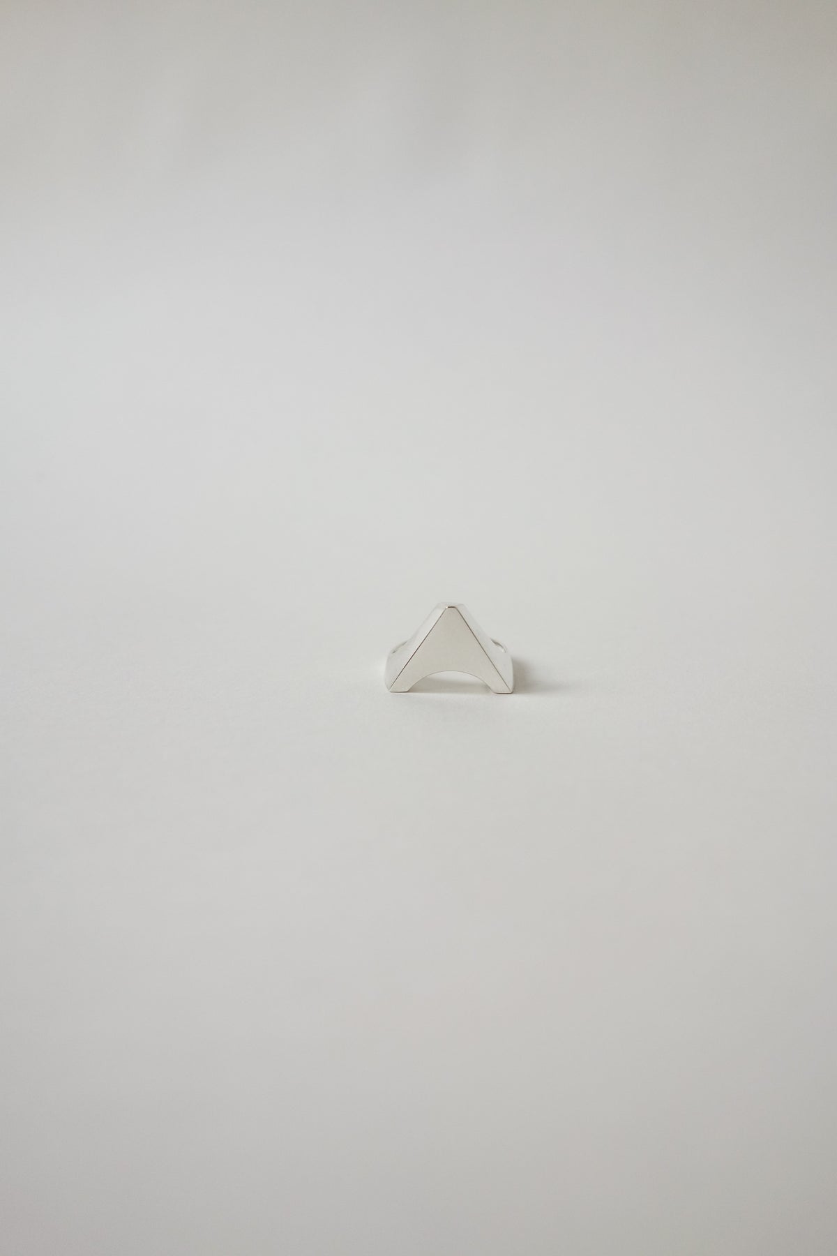 Silver triangle-shaped ring on a light gray background