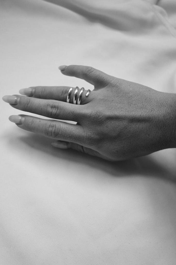 Hand wearing a silver ring on a plain background