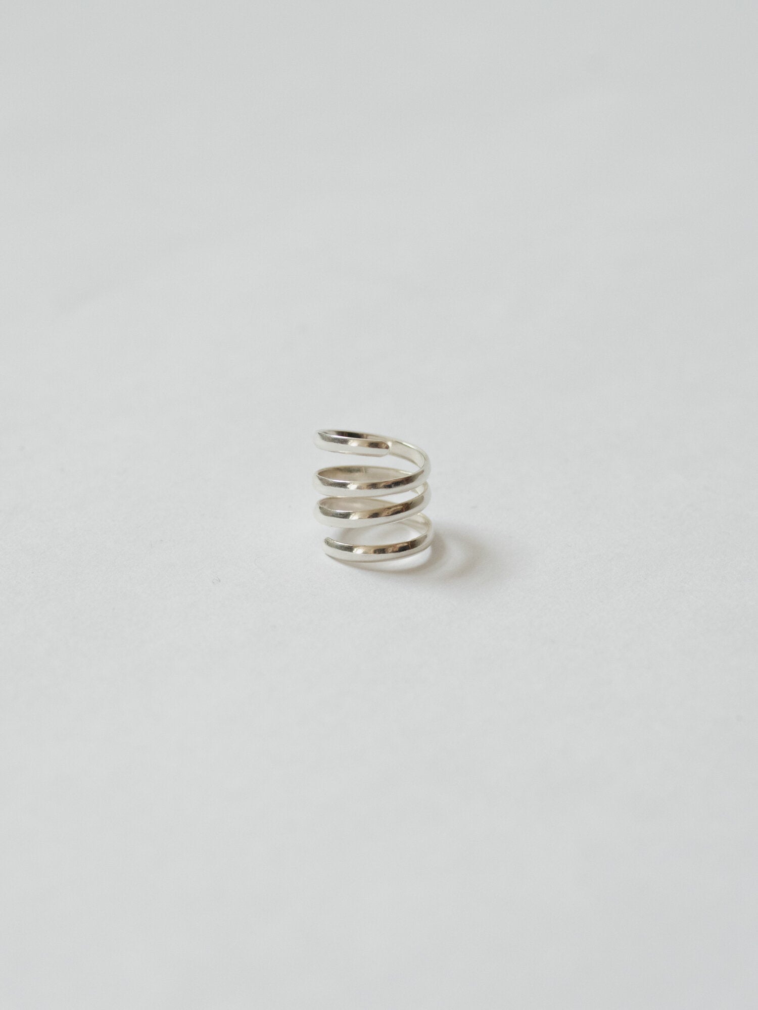 Silver spiral earring on a light gray background